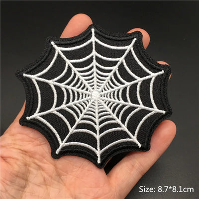 Spider web patch held in a hand with a dark background