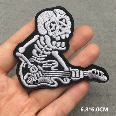 Skeleton playing guitar patch held in a hand with a gray background