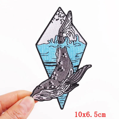 Whale patch held by a hand with dimensions '10x6.5cm' on a white background