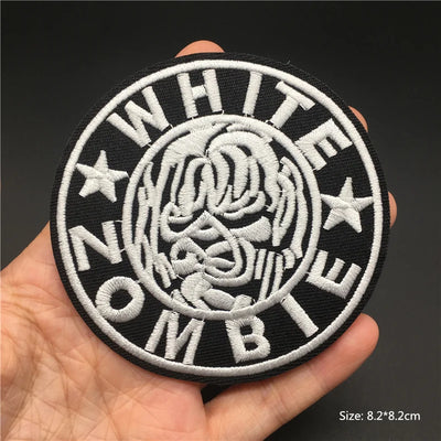 Patch with 'White Zombie' design held in a hand against a dark background