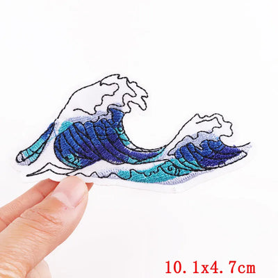 Wave-shaped embroidered patch held by a hand with dimensions displayed.