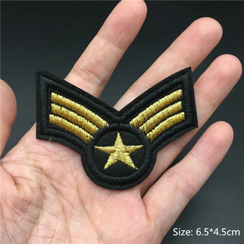 Embroidered patch with gold stripes and a star held in a hand, on a dark background.