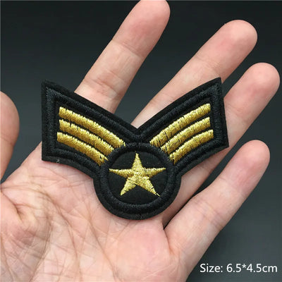 Embroidered patch with gold stripes and a star held in a hand, on a dark background.