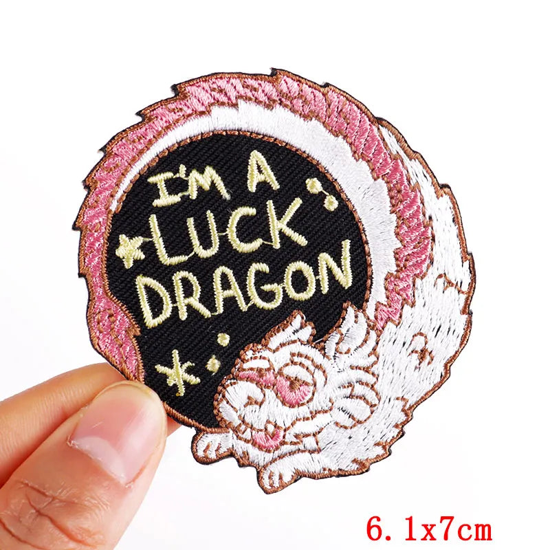 Embroidered patch with 'I'm a luck dragon' text held by a hand on a white background
