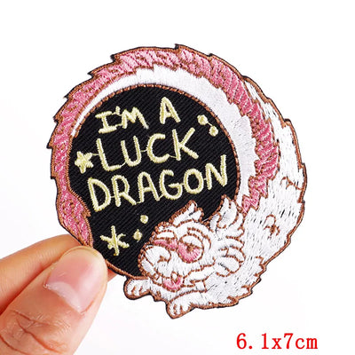 Embroidered patch with 'I'm a luck dragon' text held by a hand on a white background