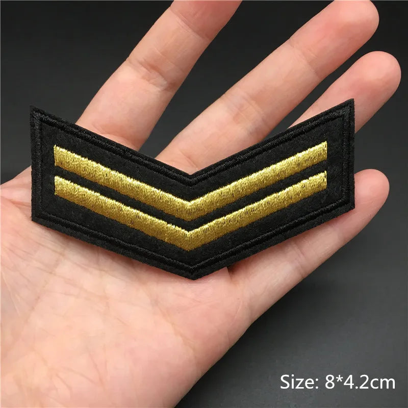 Black and gold military rank insignia held in a hand with size label