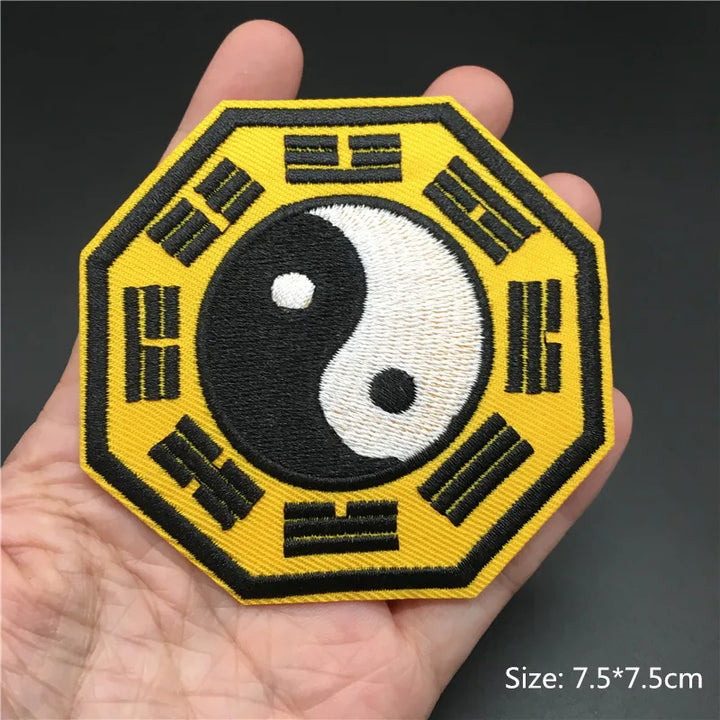 Hexagonal patch with yin yang symbol and Chinese characters held in a hand against a dark background