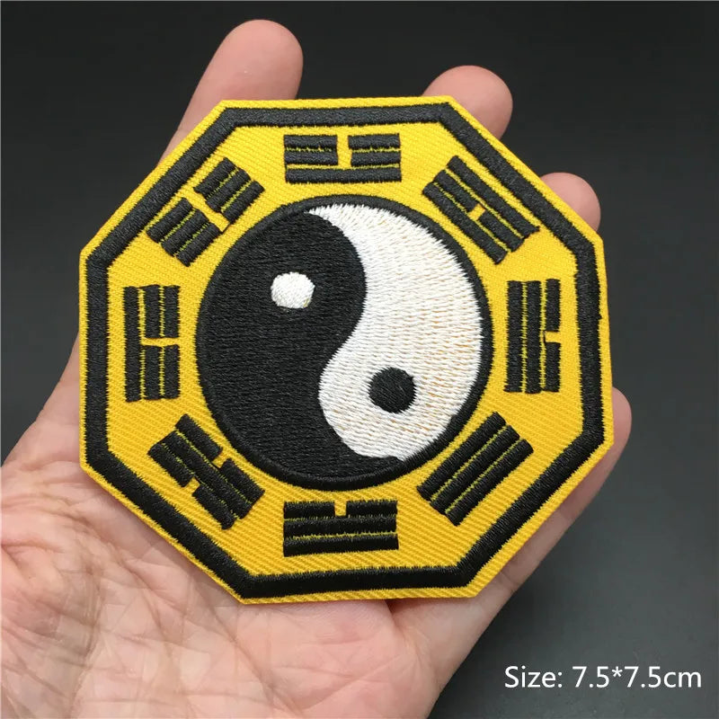 Hexagonal patch with yin yang symbol and Chinese characters held in a hand against a dark background