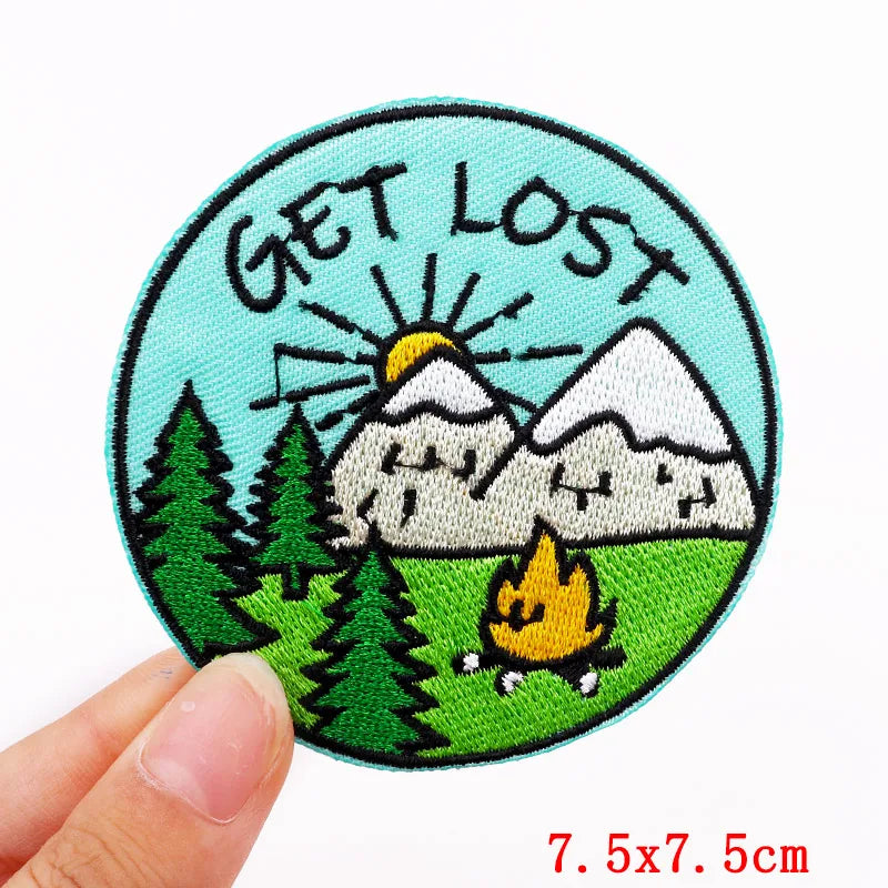 Patch with 'Get Lost' text, mountains, trees, and a campfire held by a hand.