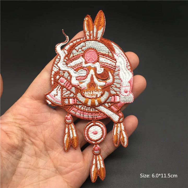 Decorative skull patch with feathers held in a hand against a dark background