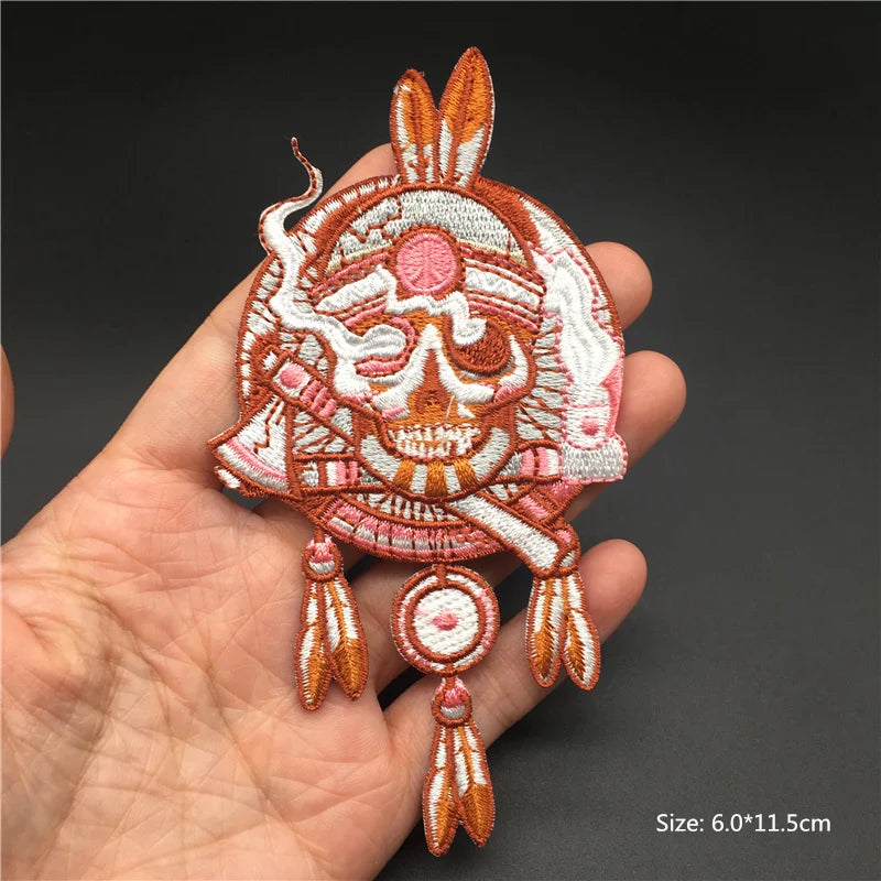 Decorative skull patch with feathers held in a hand against a dark background