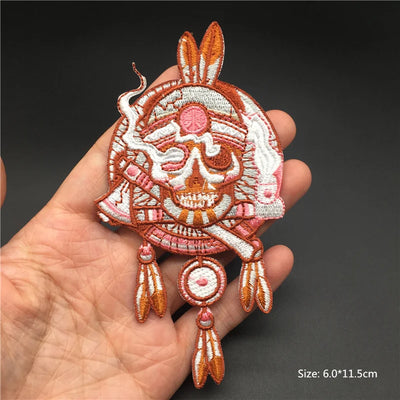 Decorative skull patch with feathers held in a hand against a dark background