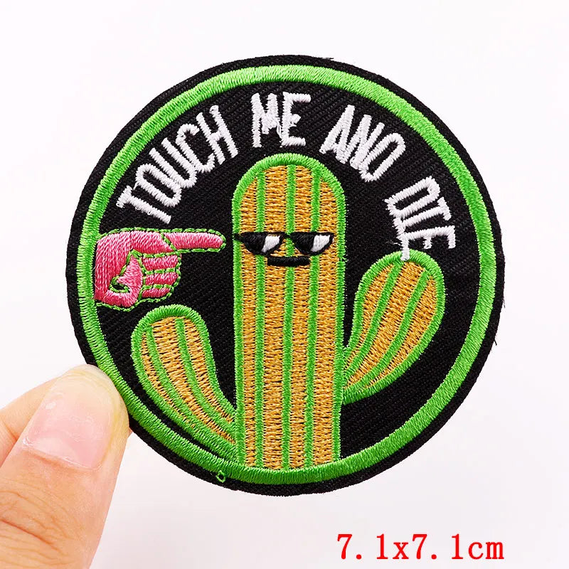 Embroidered patch with a cactus and text 'Touch Me And Die' held by a hand.