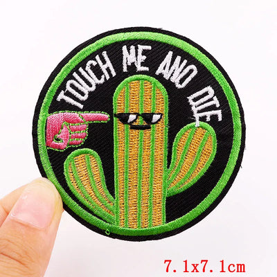 Embroidered patch with a cactus and text 'Touch Me And Die' held by a hand.