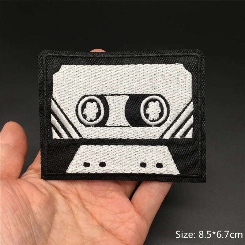Cassette tape patch held in a hand with a dark background