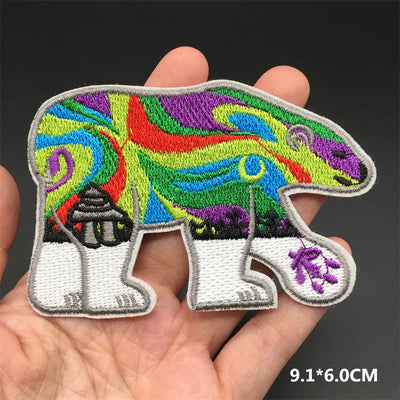 Colorful bear-shaped patch held in a hand with a dark background