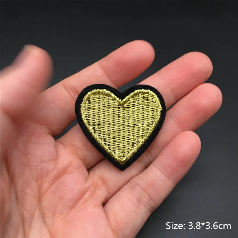 Heart-shaped patch held in a hand with a dark background