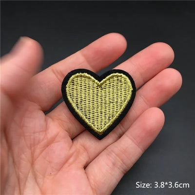 Heart-shaped patch held in a hand with a dark background