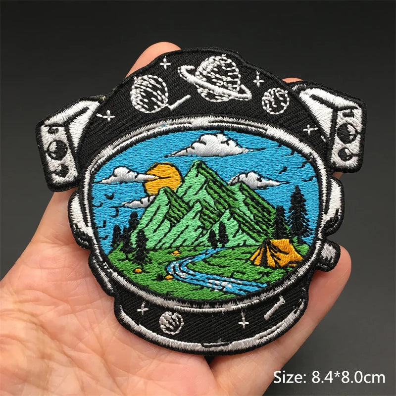 Embroidered patch with mountain and camping scene held in a hand