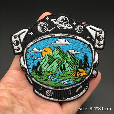 Embroidered patch with mountain and camping scene held in a hand