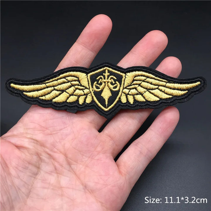 Gold wings patch held in a hand with a dark background