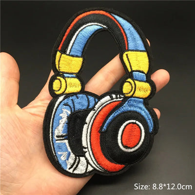 Colorful headphone-shaped patch held in a hand with a dark background