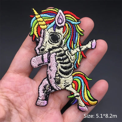 Colorful skeleton unicorn patch held in a hand with a dark background