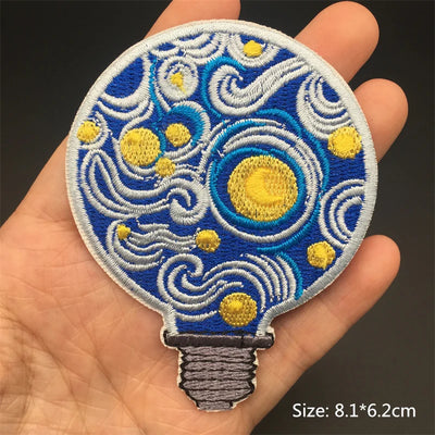 Embroidered patch of a light bulb design held in a hand with a dark background