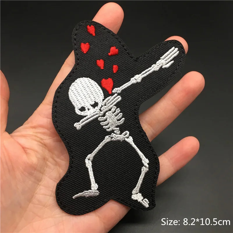 Skeleton dabbing patch with hearts held in a hand against a dark background