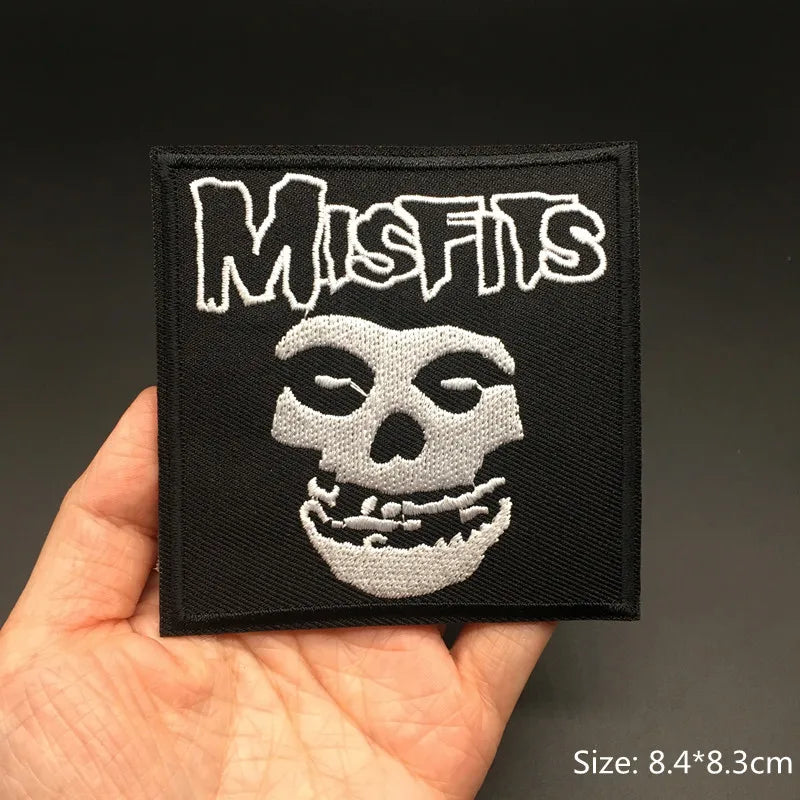 Patch with 'Misfits' logo held in a hand against a dark background