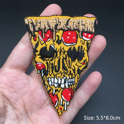 Skull-shaped patch with red eyes and yellow background held in a hand against a dark background