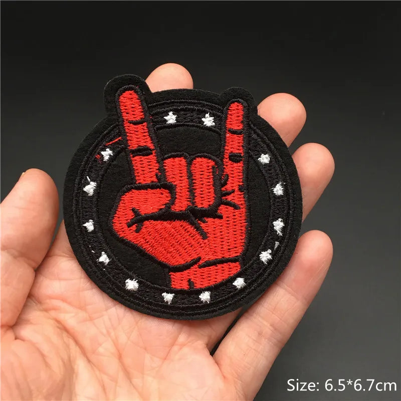 Hand holding a red and black hand gesture patch with white dots on a dark background