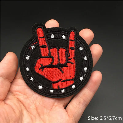 Hand holding a red and black hand gesture patch with white dots on a dark background