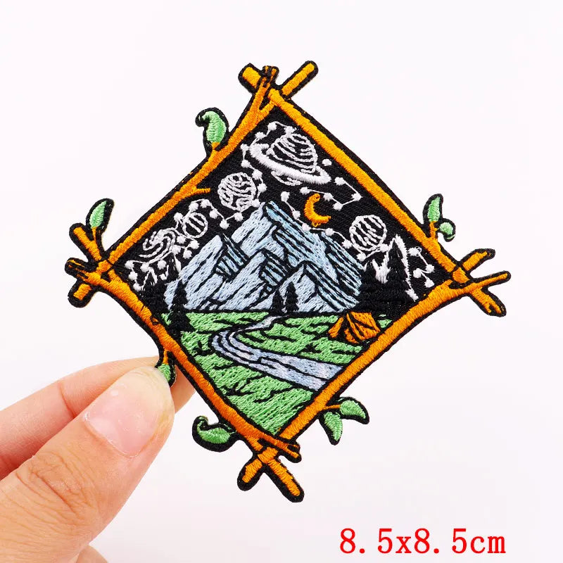 Embroidered patch with mountain design held by a hand on a white background
