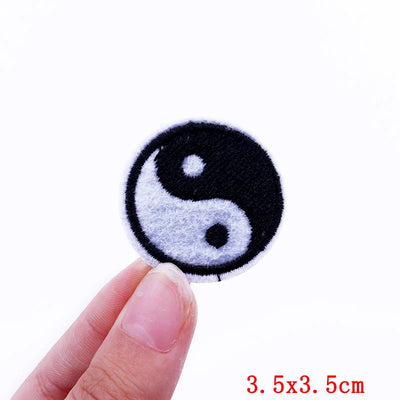 Yin and yang symbol patch held by a finger on a white background