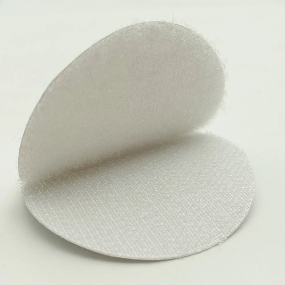 White Velcro circular adhesive pad  on a light gray background