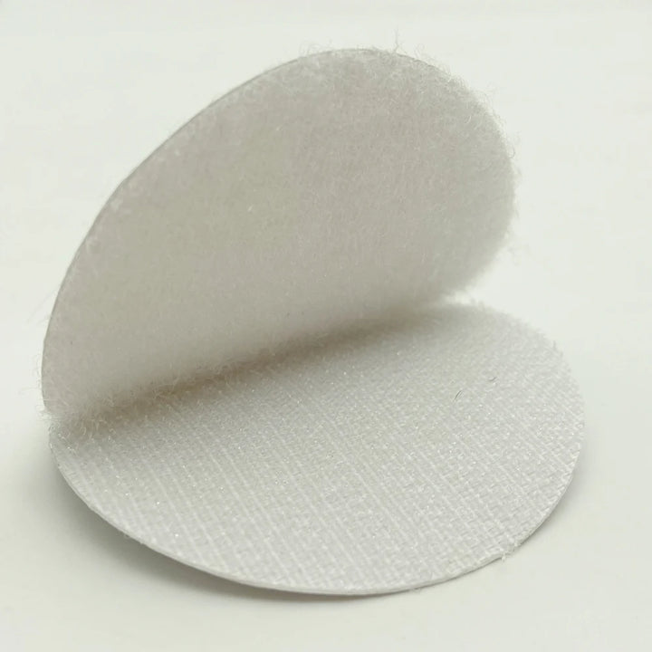 White Velcro circular adhesive pad  on a light gray background