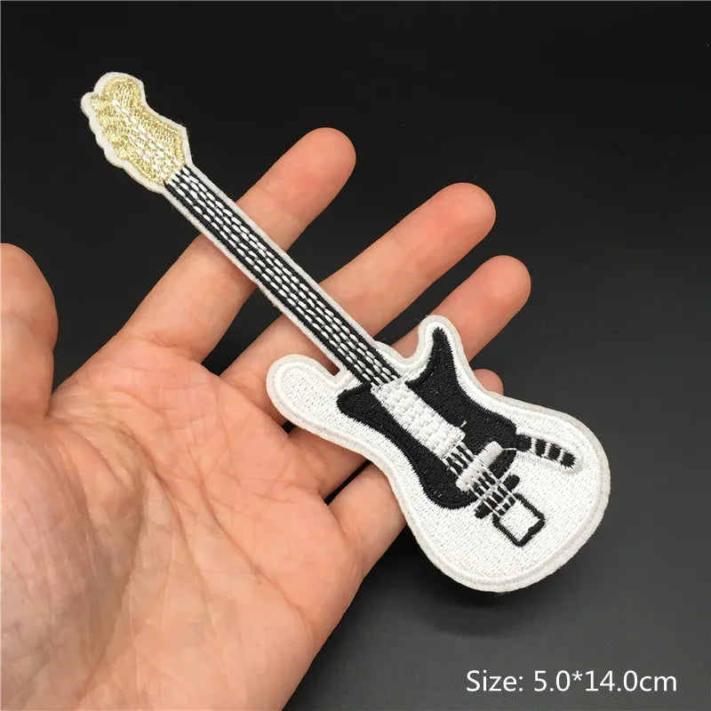 Embroidered guitar patch held in a hand with a dark background