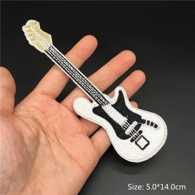 Embroidered guitar patch held in a hand with a dark background