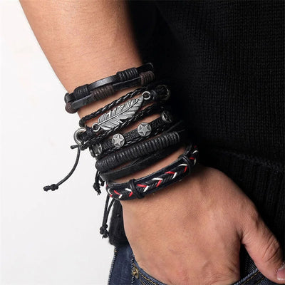 Multiple leather bracelets with metal accents on a wrist against a neutral background