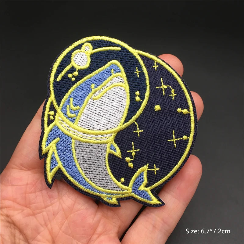 Hand holding a navy blue yellow and white embroidered dreamy moon character iron-on patch approximately 6.7x7.2cm on a dark background