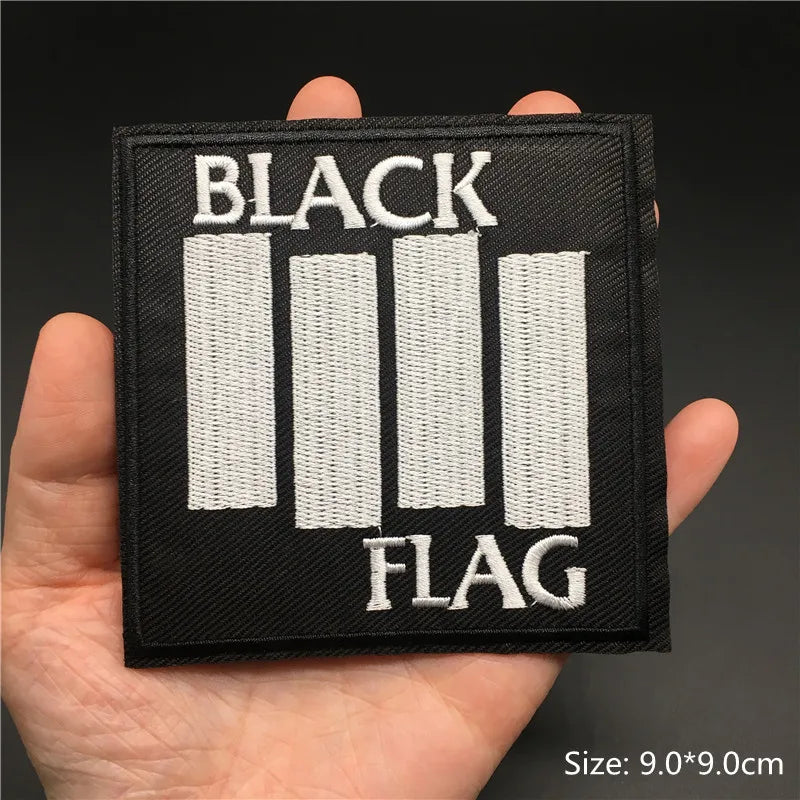 Black flag patch held in a hand with a dark background