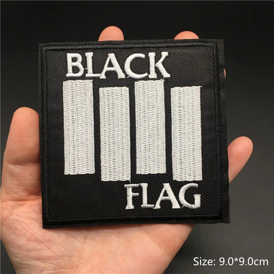 Black flag patch held in a hand with a dark background