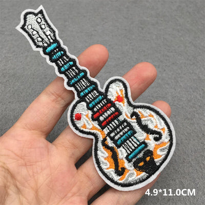 Embroidered patch of a guitar held in a hand on a gray background