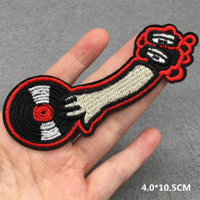 Embroidered patch of a cartoon character with a wrench held in a hand on a gray background.