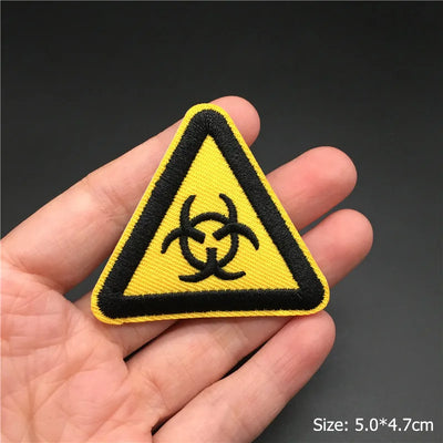 Biohazard warning patch held in a hand with a dark background
