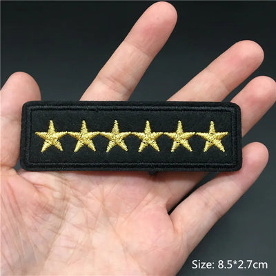 Black patch with gold stars held in a hand against a dark background