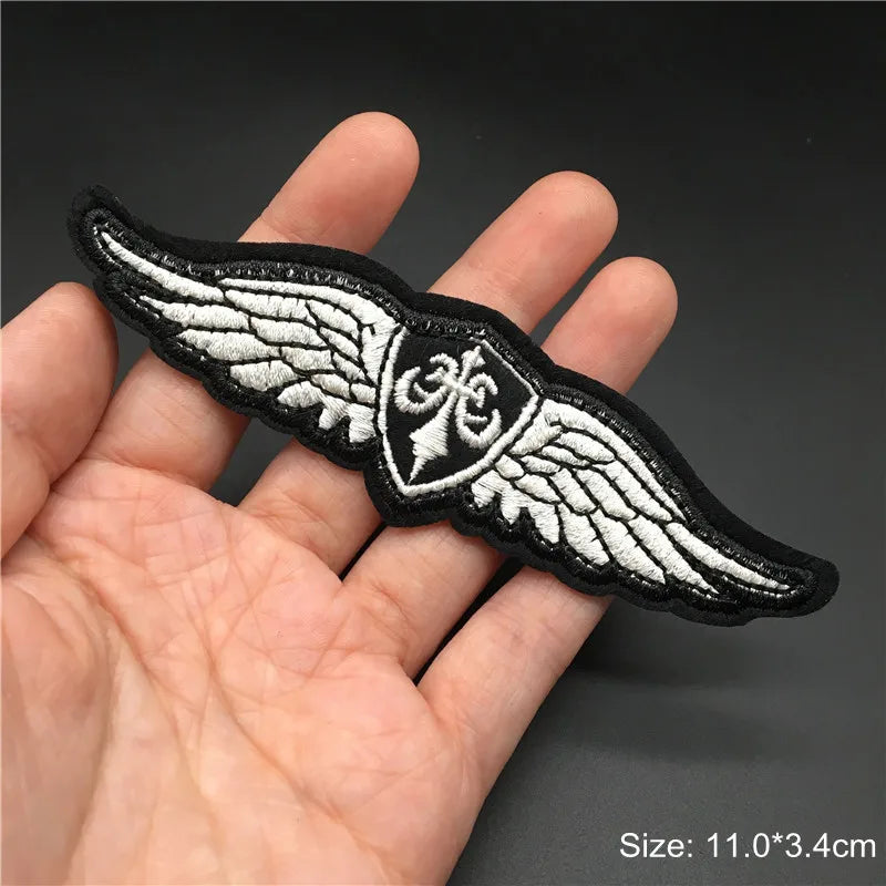 Black and white winged patch held in a hand with a dark background