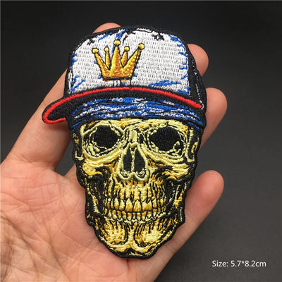 Skull patch with a crown on a cap held in a hand against a dark background