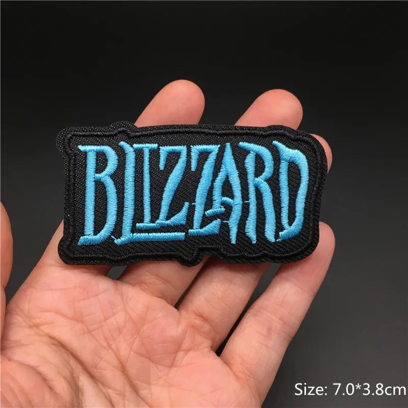 Blizzard logo patch held in a hand with a dark background